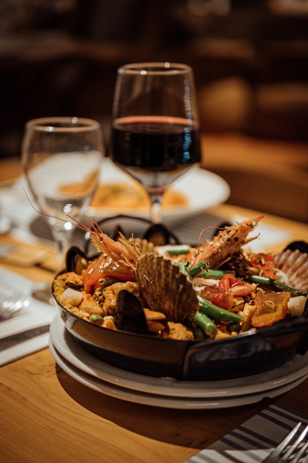 Cazuela de mariscos con langostinos, mejillones y vieiras, con una copa de vino tinto al lado