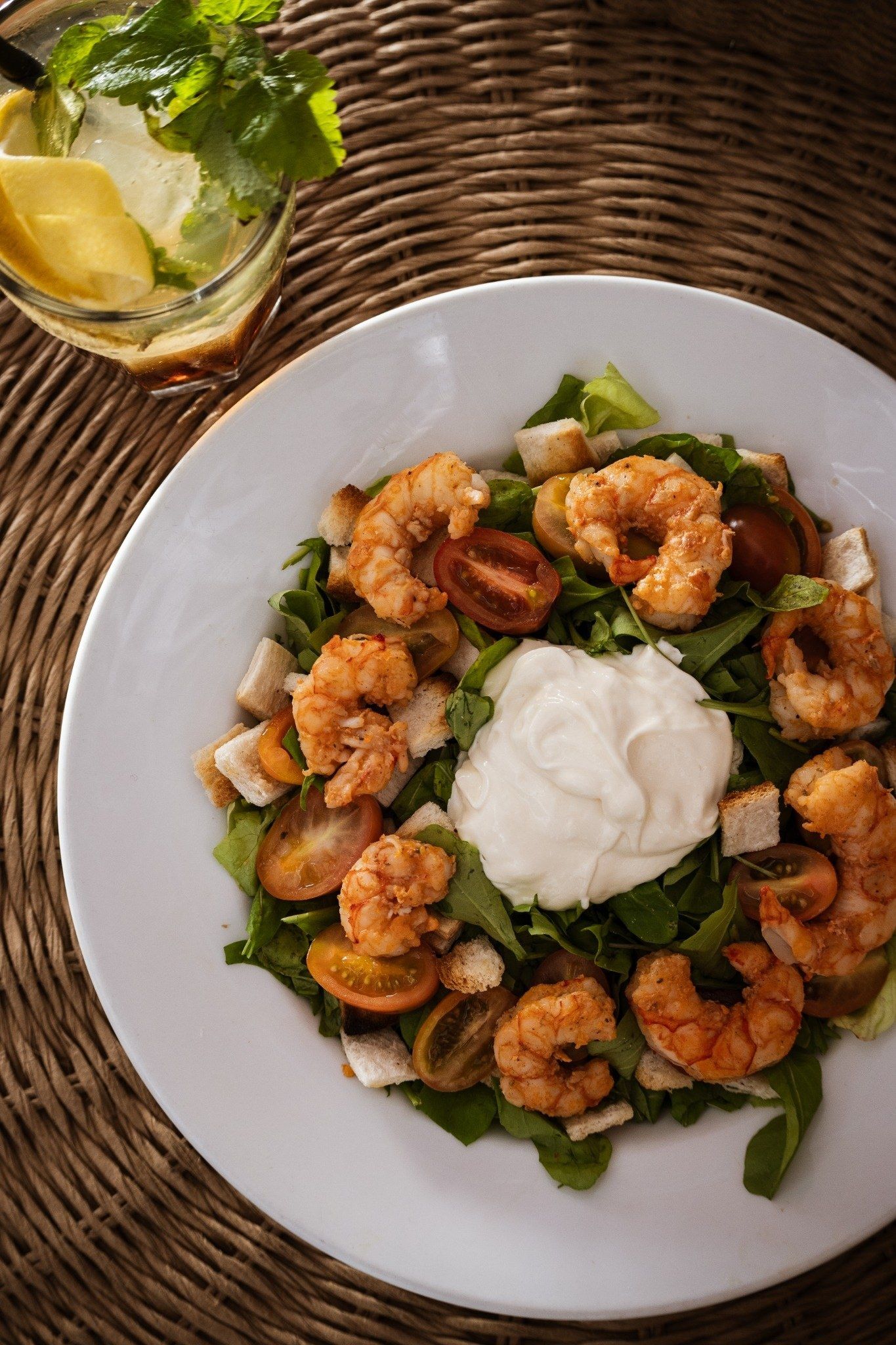 Ensalada de langostinos con burrata y tomates, servida en plato hondo blanco