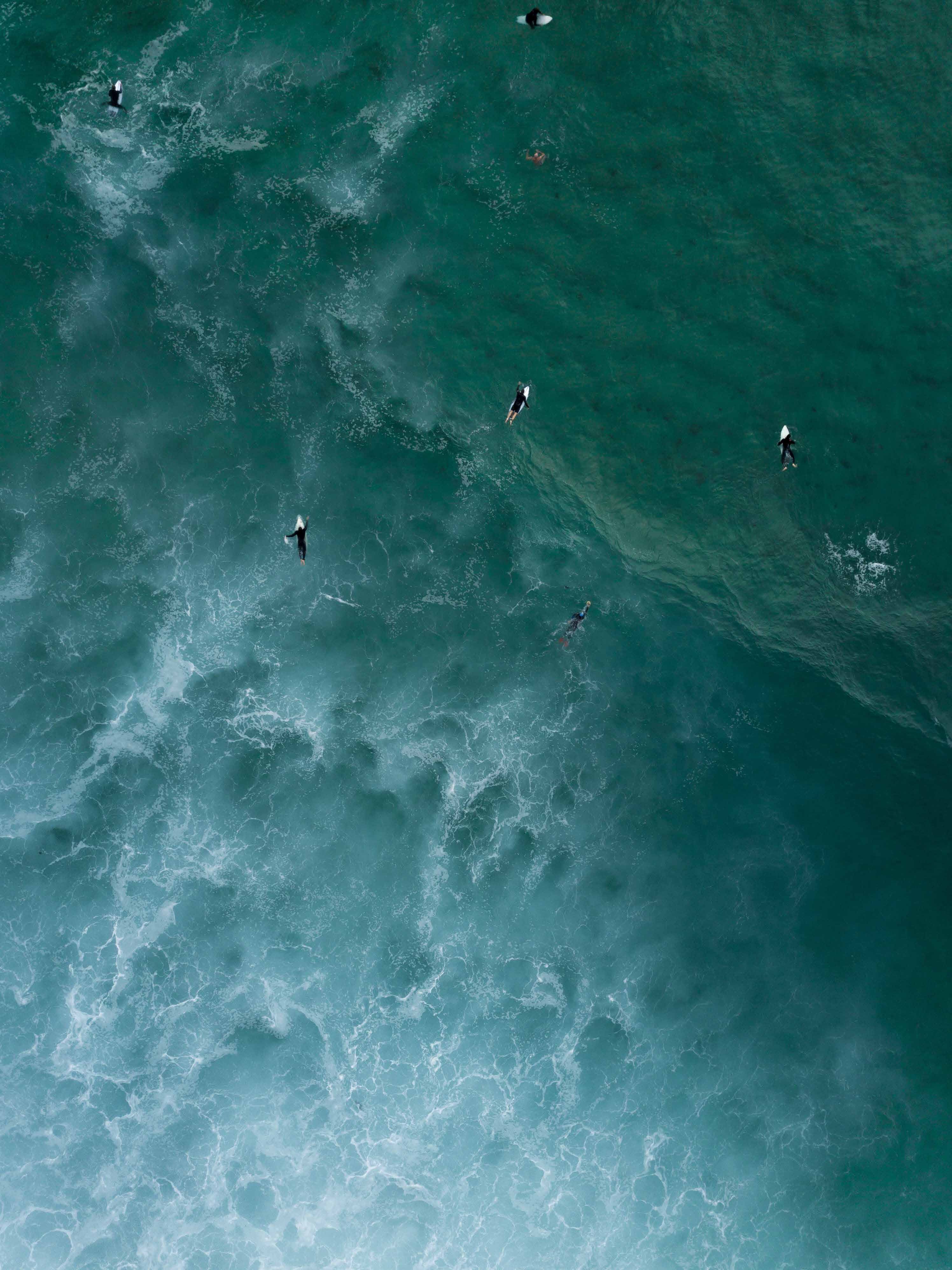 El mar de Mar del Plata desde el aire, con surfistas esperando la ola en agua verde oscuro