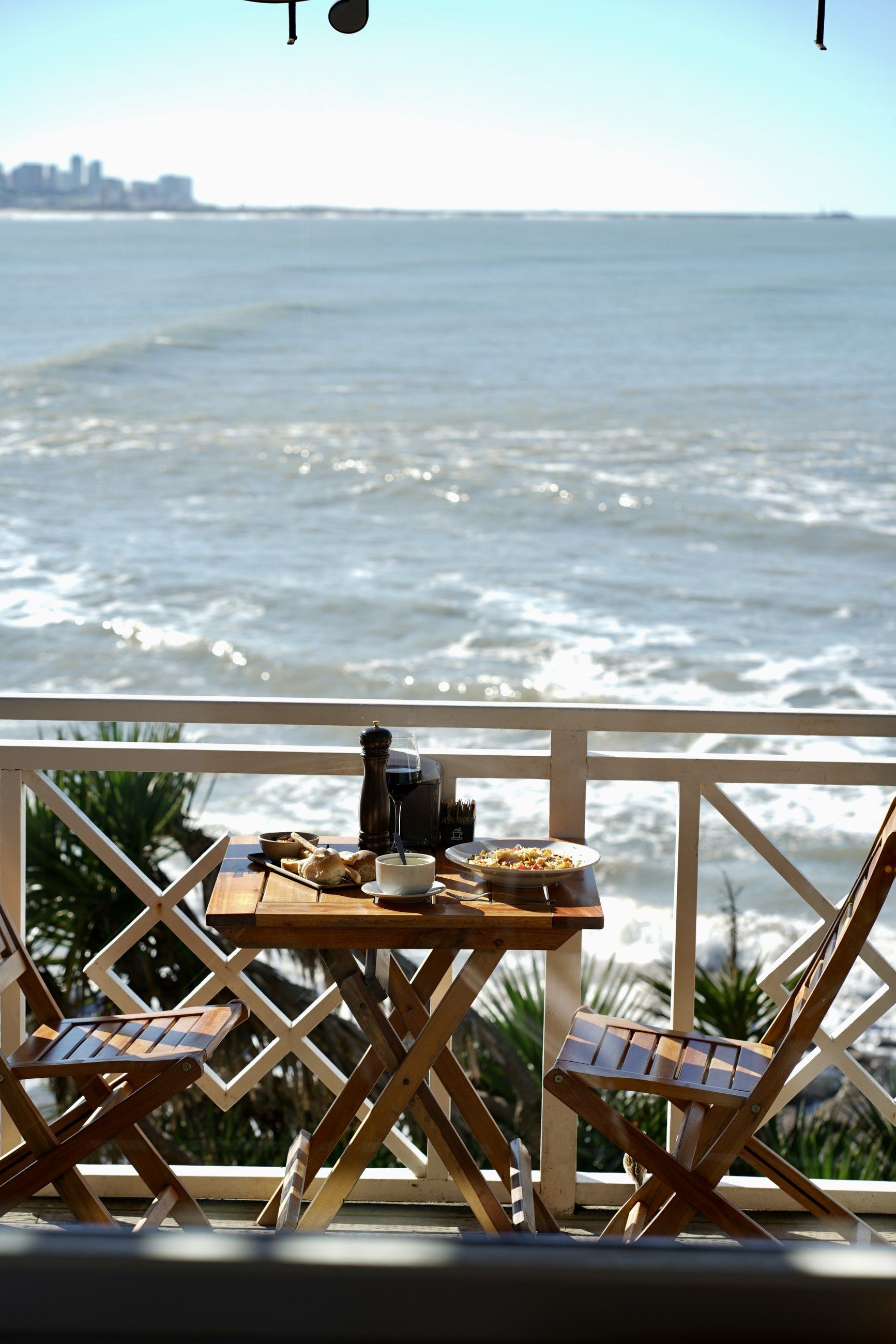 Una mesa puesta junto a la baranda, con la costa de Mar del Plata al fondo