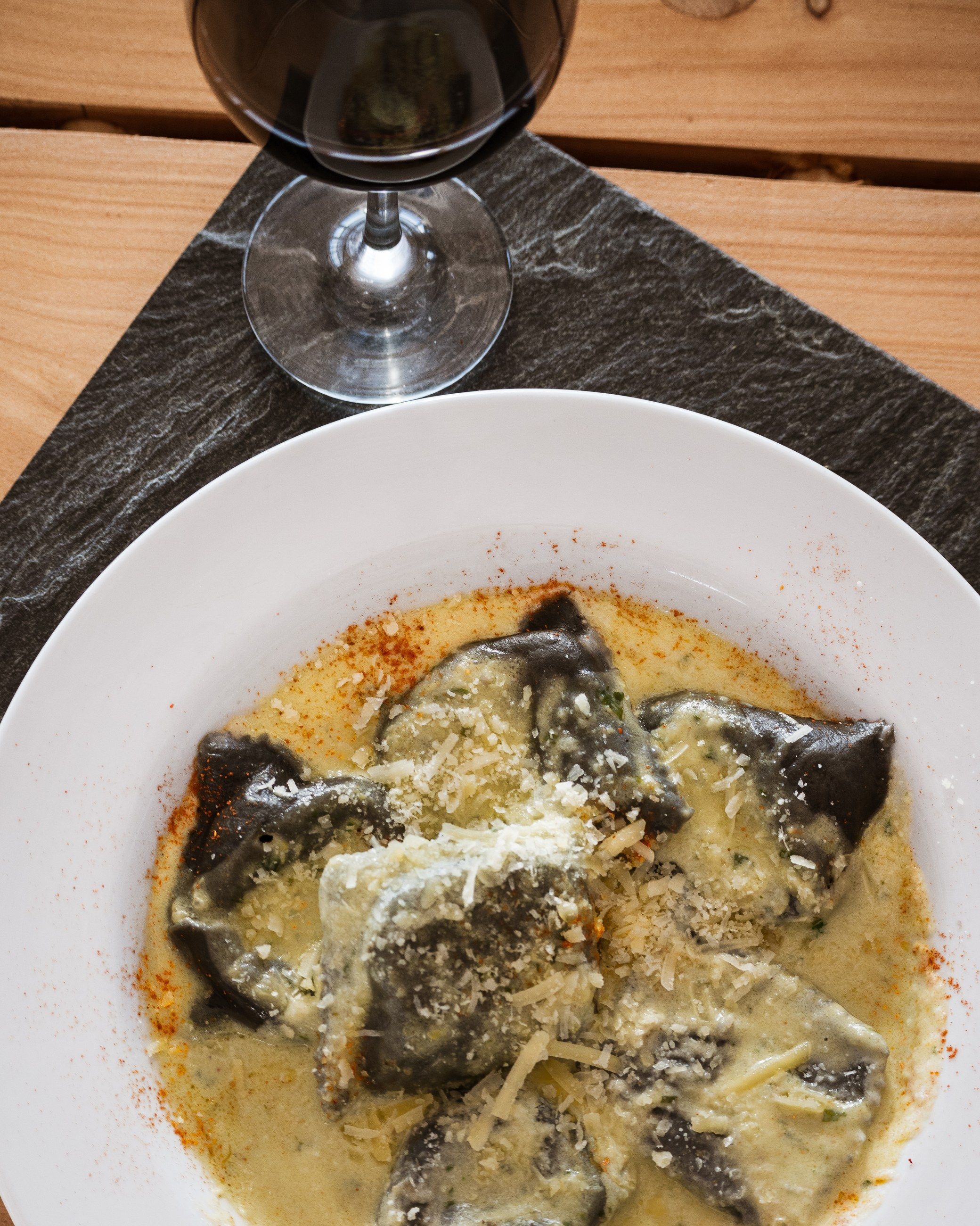 Ravioles negros en salsa de crema con queso rallado y pimentón