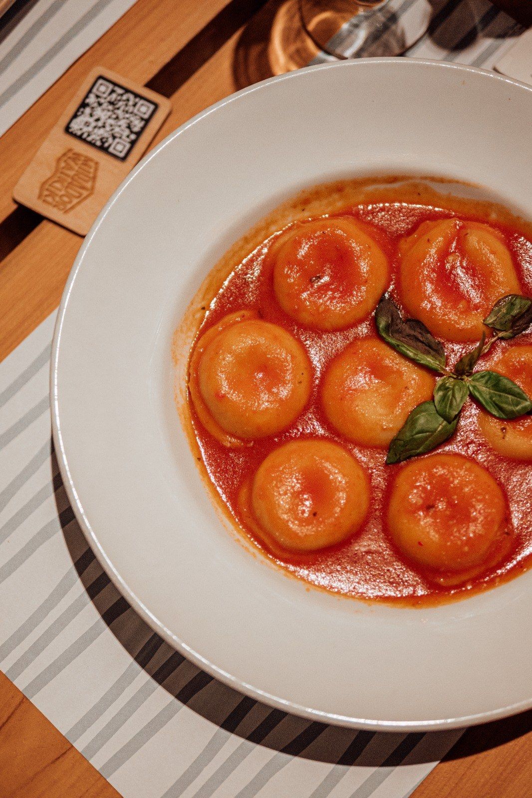 Sorrentinos en salsa de tomate con albahaca, sobre el mantel rayado