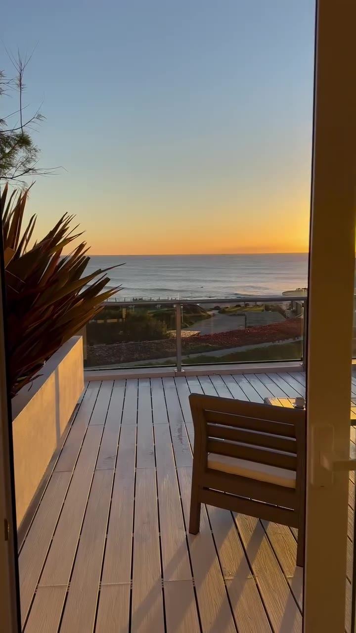 Amanecer desde la terraza del hotel: el deck de madera, una silla mirando al mar y el sol saliendo sobre el agua